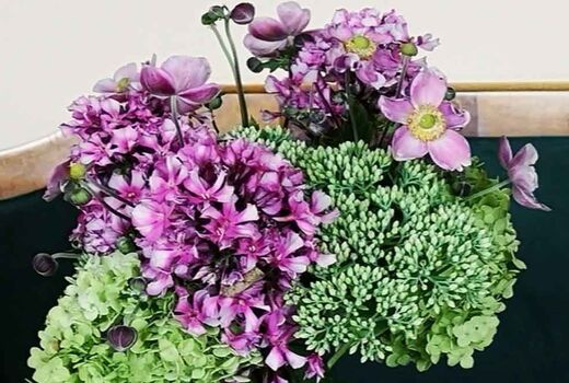 Bunter Blumenstrauß mit lila Anemonen, grüner Hortensie und Fetthenne in einer Vase