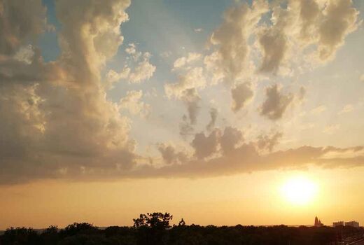 Stimmungsvoller Sonnenuntergang mit dramatischen Wolken und goldenem Licht über der weiten Landschaft.